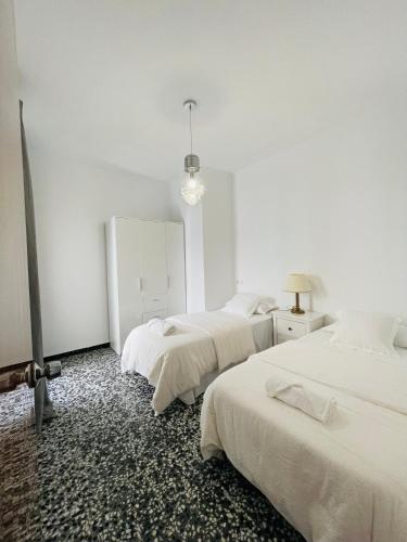 twee bedden in een kamer met witte muren en een spiegel bij Charment appartement a vinaros in Vinarós