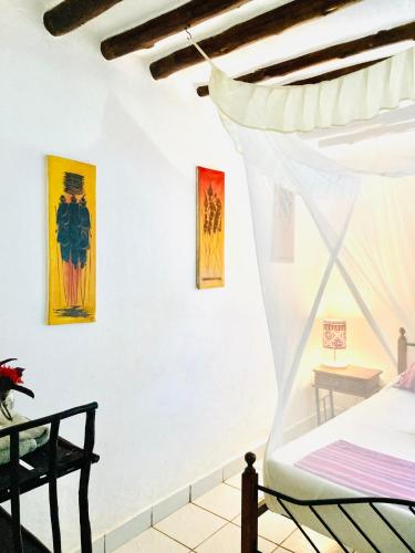 a bedroom with a bed and four paintings on the wall at Cottage Shambala la Africa in Galu