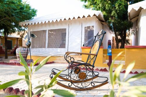 a rocking chair in front of a house at Chokhi Dhani Desert Camp in Sām