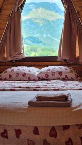 a bed with pillows and a window in a room at Cottage Forest Hill in Žabljak