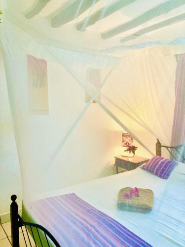 a bedroom with a bed with a canopy at Cottage Shambala la Africa in Galu