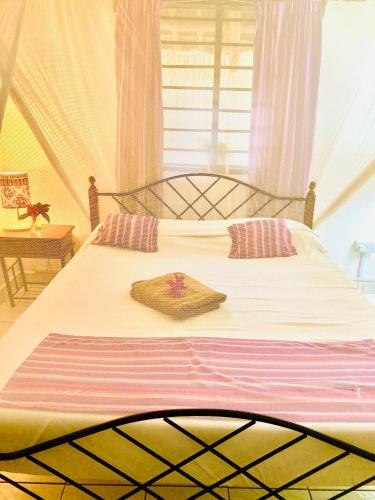 a bedroom with a large white bed with a window at Cottage Shambala la Africa in Galu