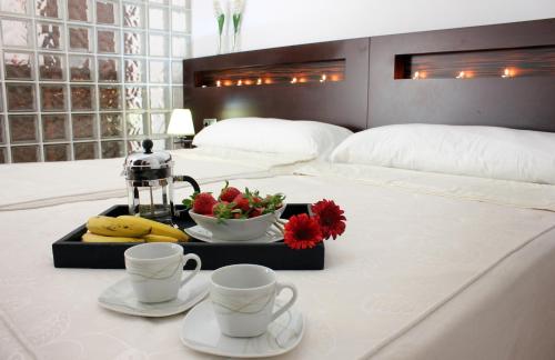 un letto con due tazze e un vassoio con frutta e fiori di La Hacienda de Don Luis a Jimena de la Frontera