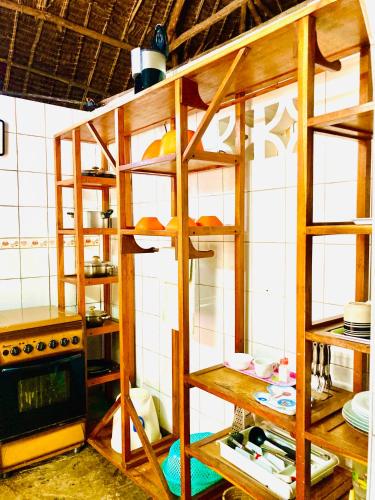 a kitchen with wooden shelves with food on them at Cottage Shambala la Africa in Galu