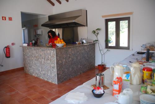 a woman in a kitchen with a counter top at Paisagem do Guadiana Turismo Rural in Alcoutim