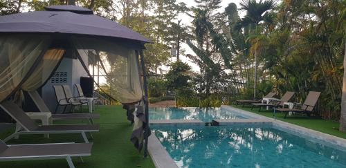 Una piscina con sillas y una sombrilla al lado de una piscina. en COCOON Koh Chang, en Ko Chang