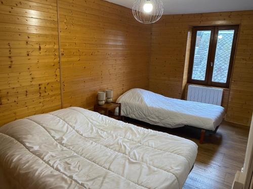 Dos camas en una habitación con paredes de madera. en Maison les papillons, en Le Mont-Dore