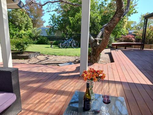 a vase of flowers on a table on a deck at Doonside Private Cottage at Grossi Point Reserve in Mapua