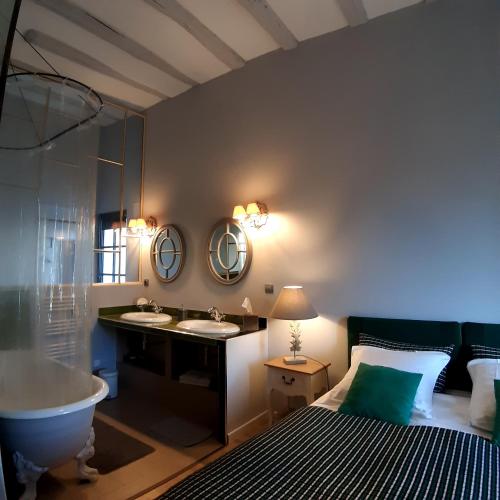 La salle de bains est pourvue d'un lit, d'une baignoire et d'un lavabo. dans l'établissement L'Arcane Du Bellay, à Montreuil-Bellay