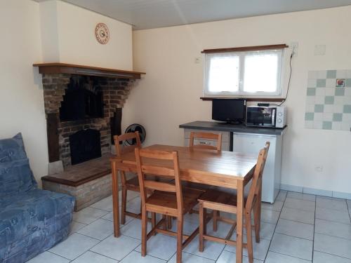 Il comprend une cuisine avec une table et des chaises en bois ainsi qu'une cheminée. dans l'établissement La chambre à four, à Frampas