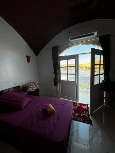 a bedroom with a purple bed and an open door at Nile View Guest House in Aswan