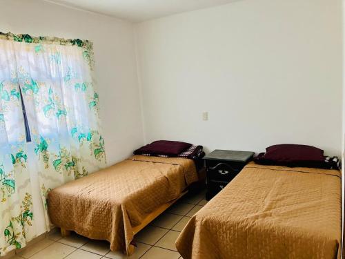 a bedroom with two beds and a window with curtains at Departamento zona industrial in San Luis Potosí