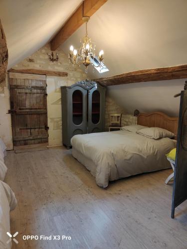 une chambre avec un grand lit et un lustre dans l'établissement Orangerie du Saulce, à Escolives-Sainte-Camille