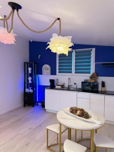 une cuisine avec des murs bleus et une table et des chaises dans l'établissement Appart Suite Balneo Jacuzzi Wifi Clim et Parking, à Mauguio