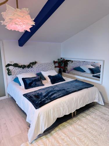 une chambre avec un grand lit avec des oreillers bleus dans l'établissement Appart Suite Balneo Jacuzzi Wifi Clim et Parking, à Mauguio