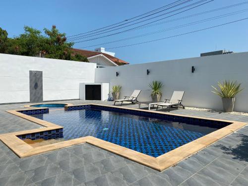 een zwembad met twee stoelen en een huis bij PATTAYA POOL VILLA 427 nearby WALKING STREET in Pattaya South