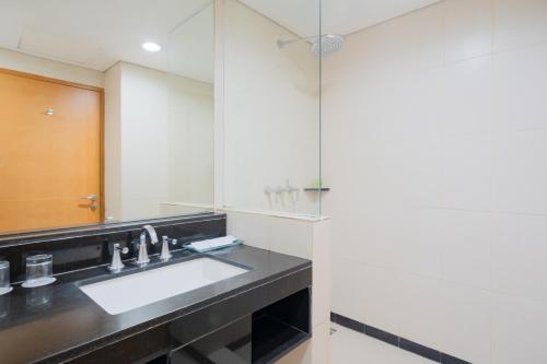 a bathroom with a sink and a mirror at The Capital Hotel Surabaya in Surabaya