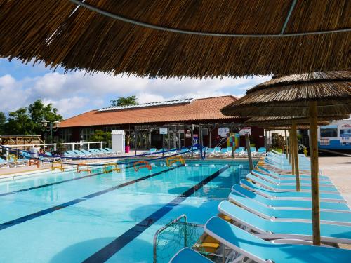 une grande piscine avec chaises et parasols dans l'établissement Natuara - L'horizon du lac - Wifi inclu, à Gastes