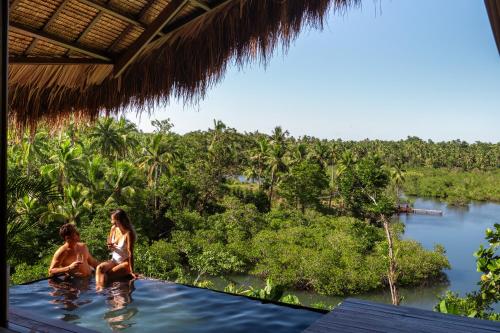 two women sitting on the edge of a pool in a river at Kalani River Villas in General Luna