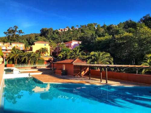 une grande piscine avec des palmiers et des maisons dans l'établissement Joli 2 pièces en bord de mer, à Théoule-sur-Mer