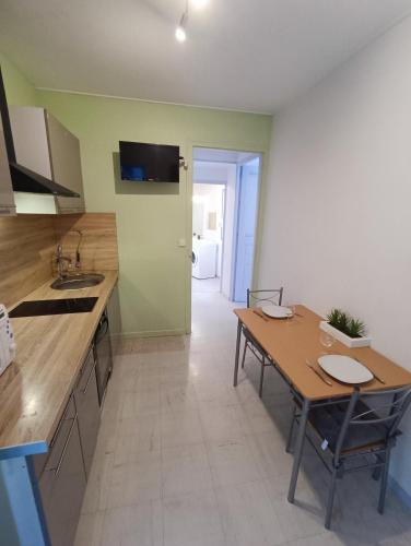 une cuisine avec une table et un évier et une table et des chaises dans l'établissement Appartement tout equipé à 600m du centre thermal, à Lamalou-les-Bains