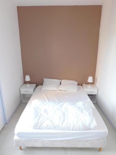 un lit blanc dans une chambre avec deux tables de nuit dans l'établissement Appartement tout equipé à 600m du centre thermal, à Lamalou-les-Bains