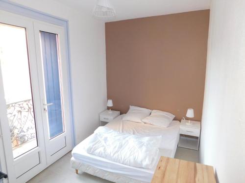 une chambre blanche avec un lit et une fenêtre dans l'établissement Appartement tout equipé à 600m du centre thermal, à Lamalou-les-Bains