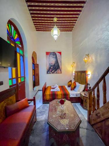 a bedroom with a bed and a couch and a table at Riad Dar El Ouedghiri in Fès