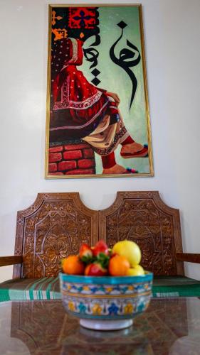 a bowl of fruit on a table with a painting at Riad Dar El Ouedghiri in Fès