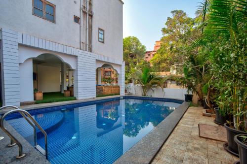 a swimming pool in front of a house at Hotel Pajaros Blu in Calangute