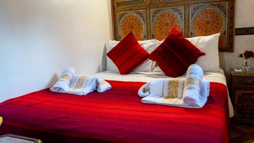 a bed with two blankets and pillows on it at Riad Dar El Ouedghiri in Fès