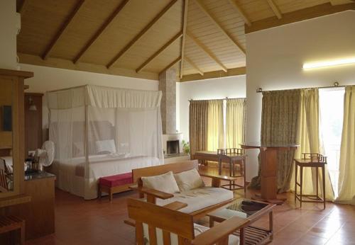 a living room with a couch and a bed at Gavadana Resort Coorg in Madikeri