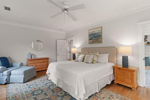 a white bedroom with a bed and a chair at Delahunt Cottage - 4218 Seventh Street in Saint Simons Island