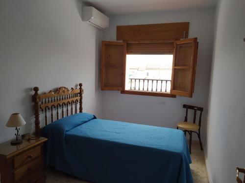 a bedroom with a blue bed and a window at Casa Montilla in Granada