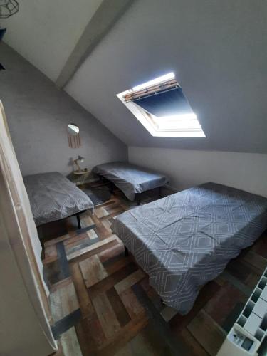 Cette chambre mansardée comprend 2 lits et une lucarne. dans l'établissement Appart'Aléa, à Sablé-sur-Sarthe