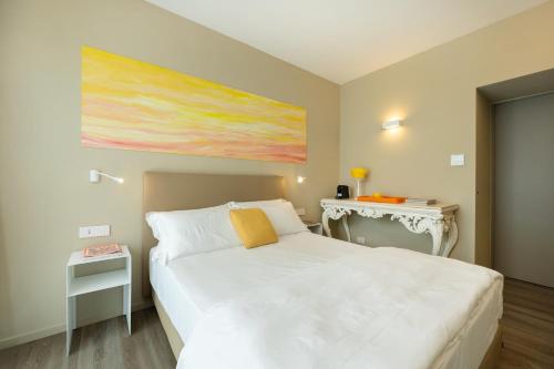 a bedroom with a white bed and a painting on the wall at Five by Capri 5 Senses in Anacapri