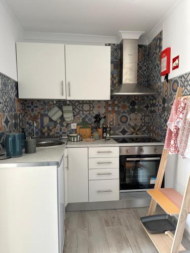 a kitchen with white cabinets and a stove at Casa da Aldeia in Alcácer do Sal