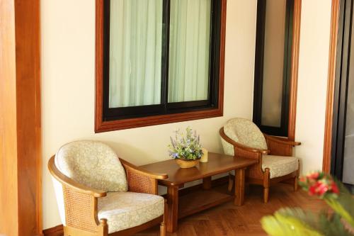 a table with two chairs and a table with flowers on it at Le-Mao Chiang Dao in Chiang Dao