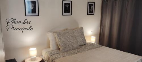 a bedroom with a bed with two candles and pictures on the wall at T3 Le Secret de Louis in Saint-Étienne-de-Saint-Geoirs