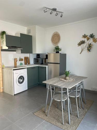 La cuisine est équipée d'une table, d'une cuisinière et d'un réfrigérateur. dans l'établissement Appartement 2 pièces vue mer, à Saint Cyprien Plage