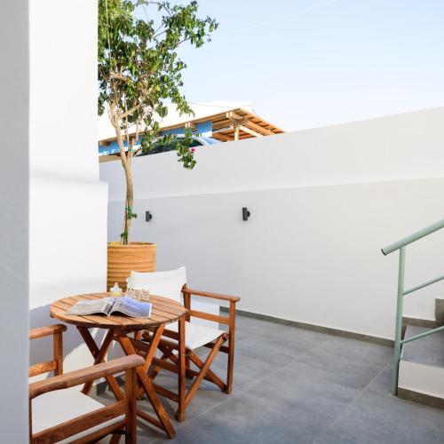 a patio with a table and chairs and a tree at Karidis Hotel in Kamari
