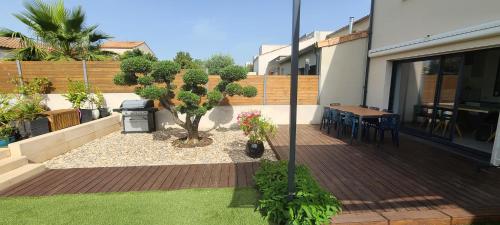 a backyard with a patio with a tree and a table at Magnifique villa à 15mn des plages in Fabrègues