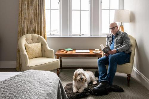 a man sitting in a chair in a room with a dog at The Porlock Weir Hotel in Porlock