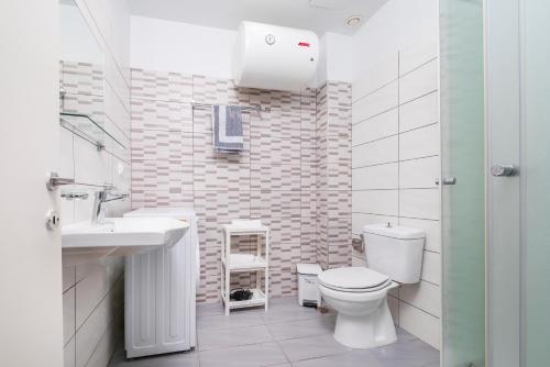 a white bathroom with a toilet and a sink at Silia apartments1 in Ampavris