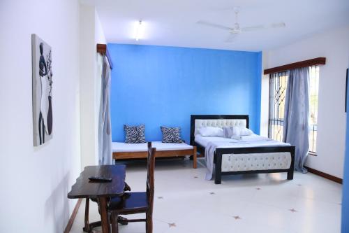 a bedroom with two beds and a blue wall at Nyali Fully Furnished Rooms and Apartments in Mombasa