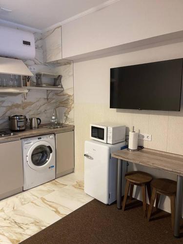 a kitchen with a table and a washing machine and a microwave at Апартаменти в центрі міста in Poltava