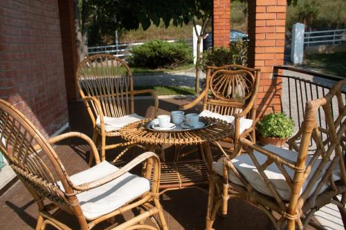 three wicker chairs and a table with a cup on it at Al frutteto in San Pietro di Feletto