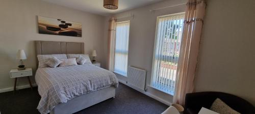 una camera da letto con un letto e due finestre di Sunrise Cottage, 2 minutes walk from the beach! a Woodhorn