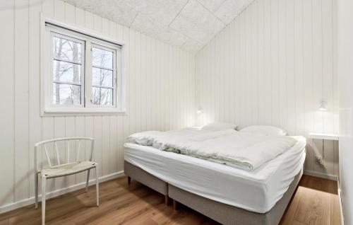 a white bedroom with a bed and a chair at Stunning Home In Glesborg With Sauna in Glesborg