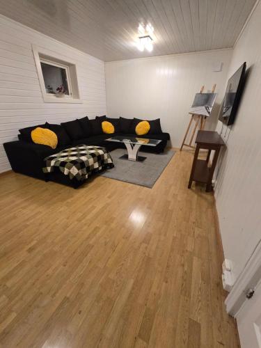 a living room with a black couch and yellow pillows at 2 rooms Hybel-leilighet, close to Tønsberg in Tønsberg